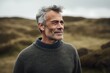© Eber Braun - Portrait of a handsome middle-aged man with gray hair and gray eyes wearing a grey sweater standing in a grassy field