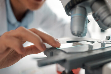 Wall Mural - i wonder what this holds. shot of a male lab tech positioning a slide under a microscope.