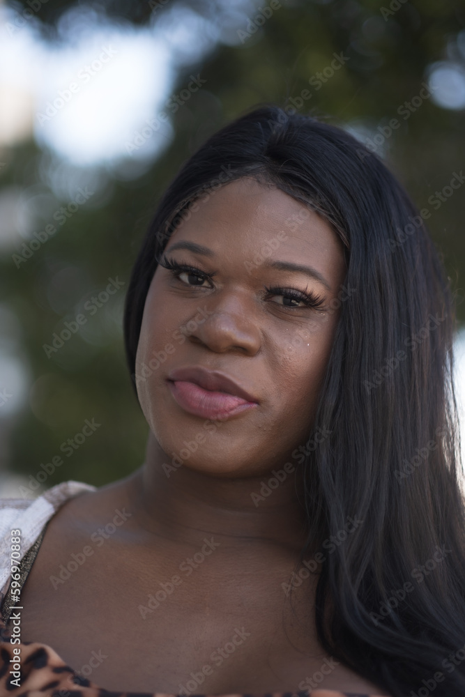 With a bold and ambitious spirit, a transwoman poses for a portrait that captures her strength and determination. A vague cityscape expresses in the bokeh of the background.