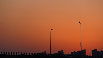 Wall Mural - the beautiful sunset view with the buildings' silhouette and orange color sky as background in the c