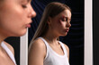 Bruised young woman near mirror on dark background, closeup. Domestic violence concept