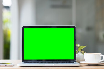 Wall Mural - Mockup of laptop computer with empty screen with coffee cup and smartphone on table of the coffee shop background,Green screen