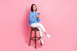 © deagreez - Photo of nice woman wear knit pullover hold smartphone sit on chair facebook twitter instagram whatsapp isolated on pink color background