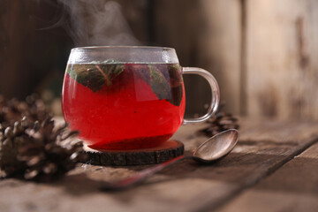 Poster - Tea with herbs, berries and fruits in a transparent cup on a wooden background