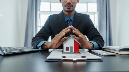 Wall Mural - Mixed race asian indian man realtor chinese people with house model in formal suit in office at desk workplace.