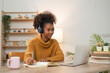 © Natee Meepian - holidays and leisure concept of young woman african women with pencil writing to diary on table at cozy home