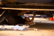 © Austockphoto - Mechanic lying underneath car making repairs using a tool