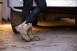 © Austockphoto - Close-up of female mechanic's boots as she stands in front of a 4wd in the garage