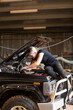© Austockphoto - Mechanic leaning under hood of 4wd car fixing the engine