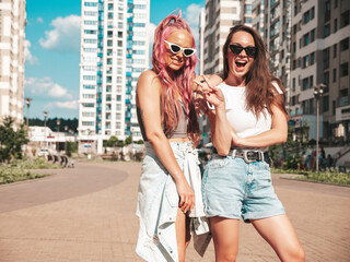 Wall Mural - Two young beautiful smiling hipster female in trendy summer clothes. Sexy carefree women posing in the street. Positive pure models having fun at sunset, hugging and going crazy. In sunglasses