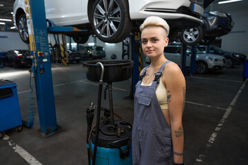 Wall Mural - Woman auto repairman stands with a device for draining oil