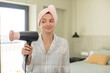 © kues1 - young pretty woman smiling and looking with a happy confident expression. hair dryer concept