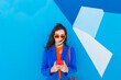 © VISTA by Westend61 - Fashionable young woman using smart phone in front of blue wall