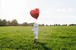 © VISTA by Westend61 - Girl dressed as astronaut walking on meadow holding heart shape balloon