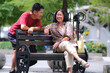 © Simon - Adult couple chatting on a park bench on a road side