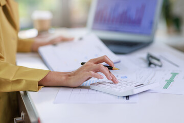 Concept of business invesment or woman working,Closeup businesswoman checking her invesment plan with analyzing document and business investment graph data by using calculator and computer laptop