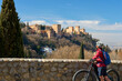 nice active senior woman cycling with her electric mountain bike in Granada below the world heritage site of Alhambra, Granada, Andalusia,  Spain