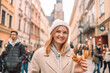 Beautiful young female tourist in stylish clothes holding pretzel obwarzanek on the market square in Krakow in Poland. High quality photo
