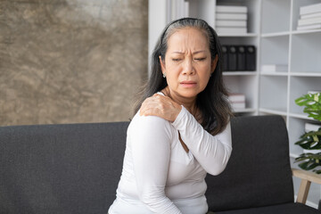 Wall Mural - Middle aged asian woman suffers from shoulder joint pain or osteoporosis.