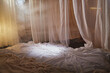 Light, soft transparent curtains in room. Canopy around bed with gentle light and blurring in evening. Boudoir. Concept of comfort in house and bedroom. Location and background for photo shoot