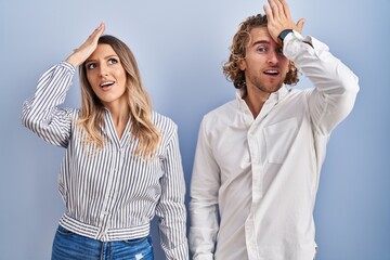 Poster - Young couple standing over blue background surprised with hand on head for mistake, remember error. forgot, bad memory concept.