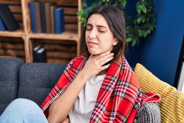 Wall Mural - Young beautiful hispanic woman suffering for throat pain sitting on sofa at park