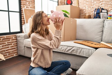 Poster - Young woman smiling confident holding piggy bank at new home