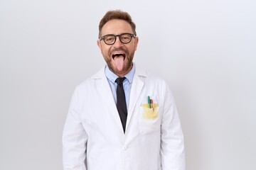 Sticker - Middle age doctor man with beard wearing white coat sticking tongue out happy with funny expression. emotion concept.