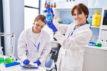 Sticker - Two women scientists holding test tube writing on document at laboratory