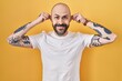 © Krakenimages.com - Young hispanic man with tattoos standing over yellow background smiling pulling ears with fingers, funny gesture. audition problem