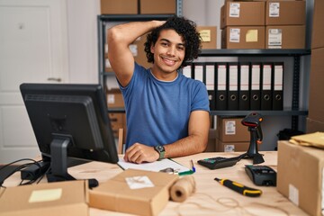 Canvas Print - Hispanic man with curly hair working at small business ecommerce smiling confident touching hair with hand up gesture, posing attractive and fashionable