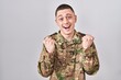 © Krakenimages.com - Young man wearing camouflage army uniform celebrating surprised and amazed for success with arms raised and open eyes. winner concept.
