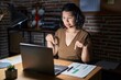 © Krakenimages.com - Young hispanic woman working at the office at night pointing down looking sad and upset, indicating direction with fingers, unhappy and depressed.