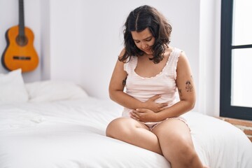 Sticker - Young woman suffering for menstrual pain sitting on bed at bedroom