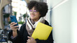© Krakenimages.com - Young african american woman smiling confident holding folder using smartphone at street