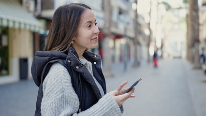 Wall Mural - Young beautiful hispanic woman smiling confident using smartphone at street