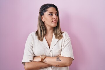 Wall Mural - Blonde woman standing over pink background looking to the side with arms crossed convinced and confident