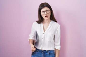 Canvas Print - Young caucasian woman holding laptop in shock face, looking skeptical and sarcastic, surprised with open mouth