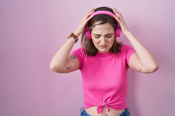 Poster - Blonde caucasian woman listening to music using headphones suffering from headache desperate and stressed because pain and migraine. hands on head.