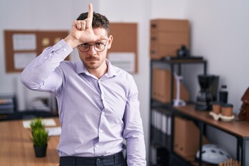 Sticker - Young hispanic man at the office making fun of people with fingers on forehead doing loser gesture mocking and insulting.