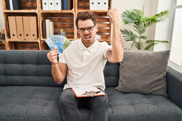 Poster - Young hispanic man working on couple therapy at consultation office holding chilean pesos annoyed and frustrated shouting with anger, yelling crazy with anger and hand raised