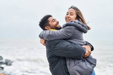 Canvas Print - Man and woman couple smiling confident hugging each other at seaside