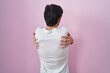 © Krakenimages.com - Young hispanic man standing over pink background hugging oneself happy and positive from backwards. self love and self care