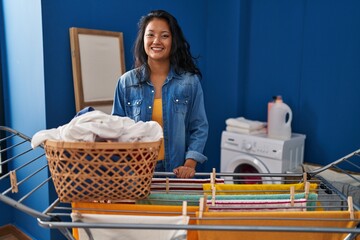 Wall Mural - Young asian woman hanging clothes at clothesline with a happy and cool smile on face. lucky person.