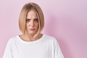 Wall Mural - Young caucasian woman standing over pink background skeptic and nervous, frowning upset because of problem. negative person.