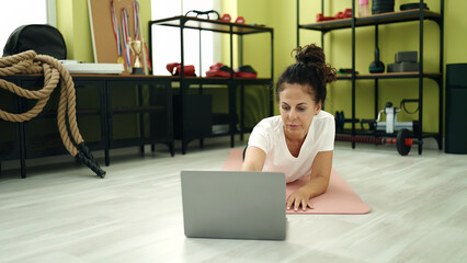 Wall Mural - Middle age hispanic woman training online core exercise at sport center