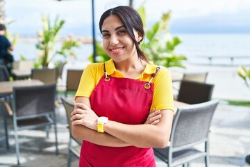 Poster - Young beautiful arab woman waitress smiling confident standing with arms crossed gesture at coffee shop terrace