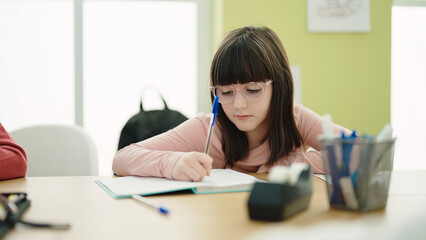 Poster - Adorable hispanic girl student writing on notebook at classroom