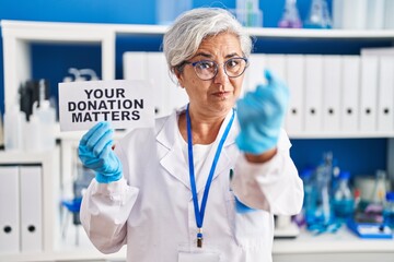 Sticker - Middle age woman with grey hair working at scientist laboratory holding your donation matters banner annoyed and frustrated shouting with anger, yelling crazy with anger and hand raised