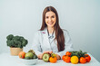 © VisualProduction - Beautiful nutritionist smiling at camera. Female nutritionist with fruit and vegetables on table. Generative AI